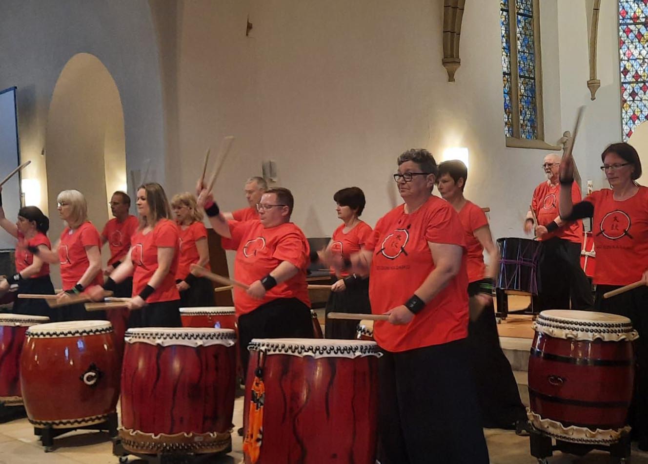 Das Foto zeigt ein großes Trommelensemble mit Instrumenten.
