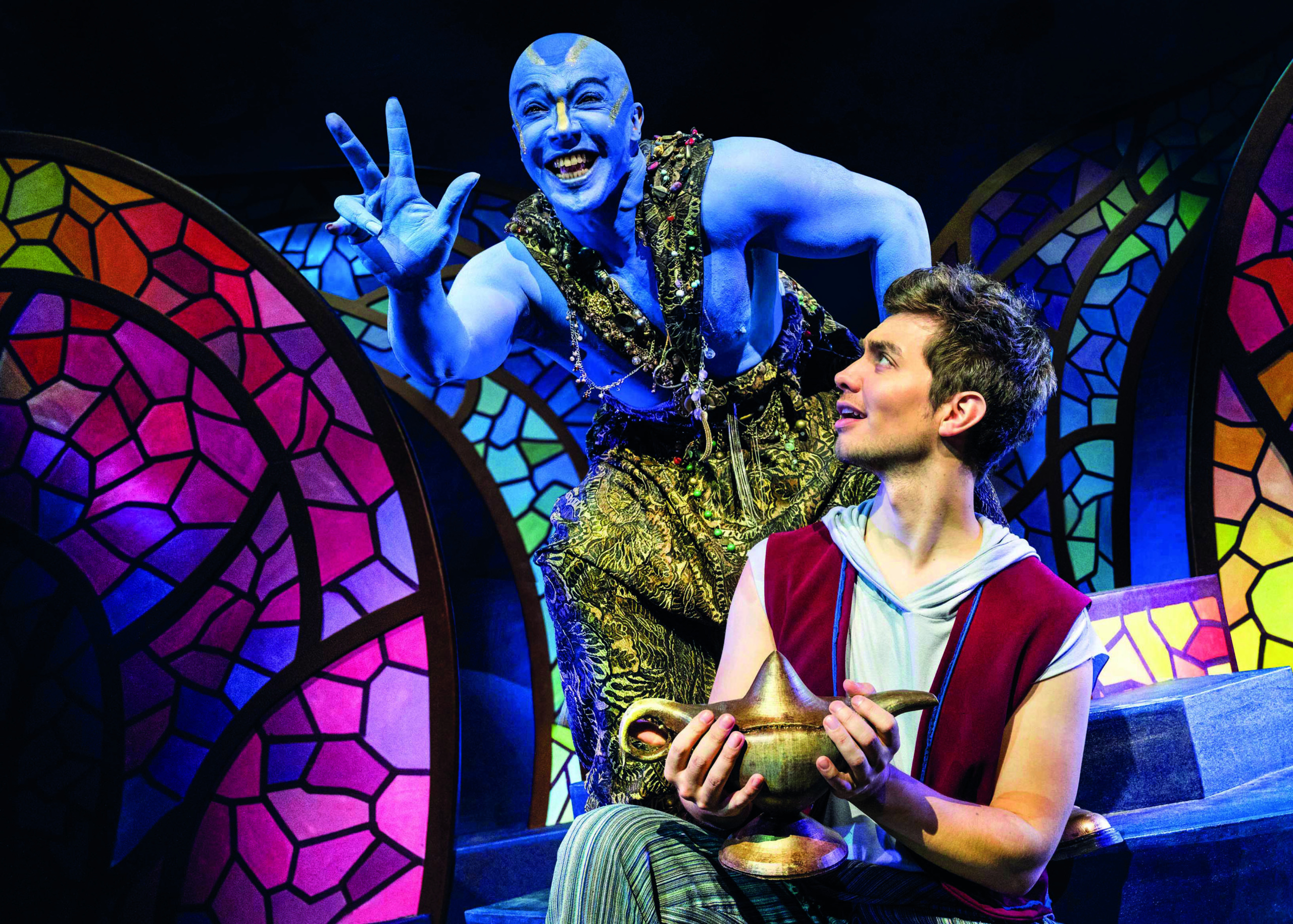 Aladin hält die Wunderlampe in der Hand, der Geist erscheint hinter ihm.