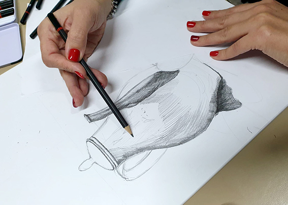 Eine Hand hält einen Bleistift und zeichnet eine Skizze.