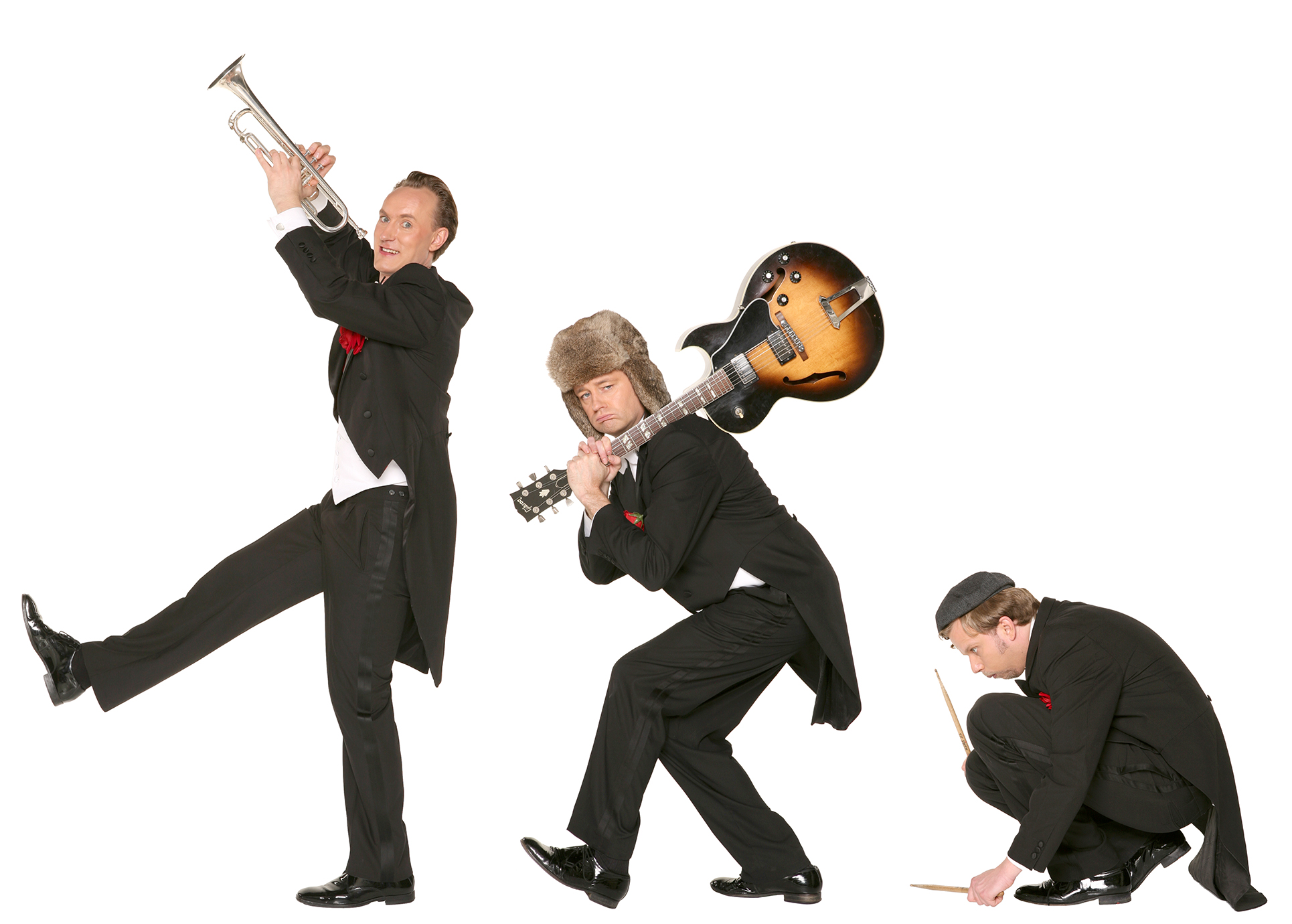 Drei Musiker stehen nebeneinander und schauen lustig in die Kamera. Der erste hält eine Trompete, der Mittlere trägt eine Gitarre auf der Schulter und der Musiker ganz rechts schlägt mit seinen Schlagstöcken auf den Boden