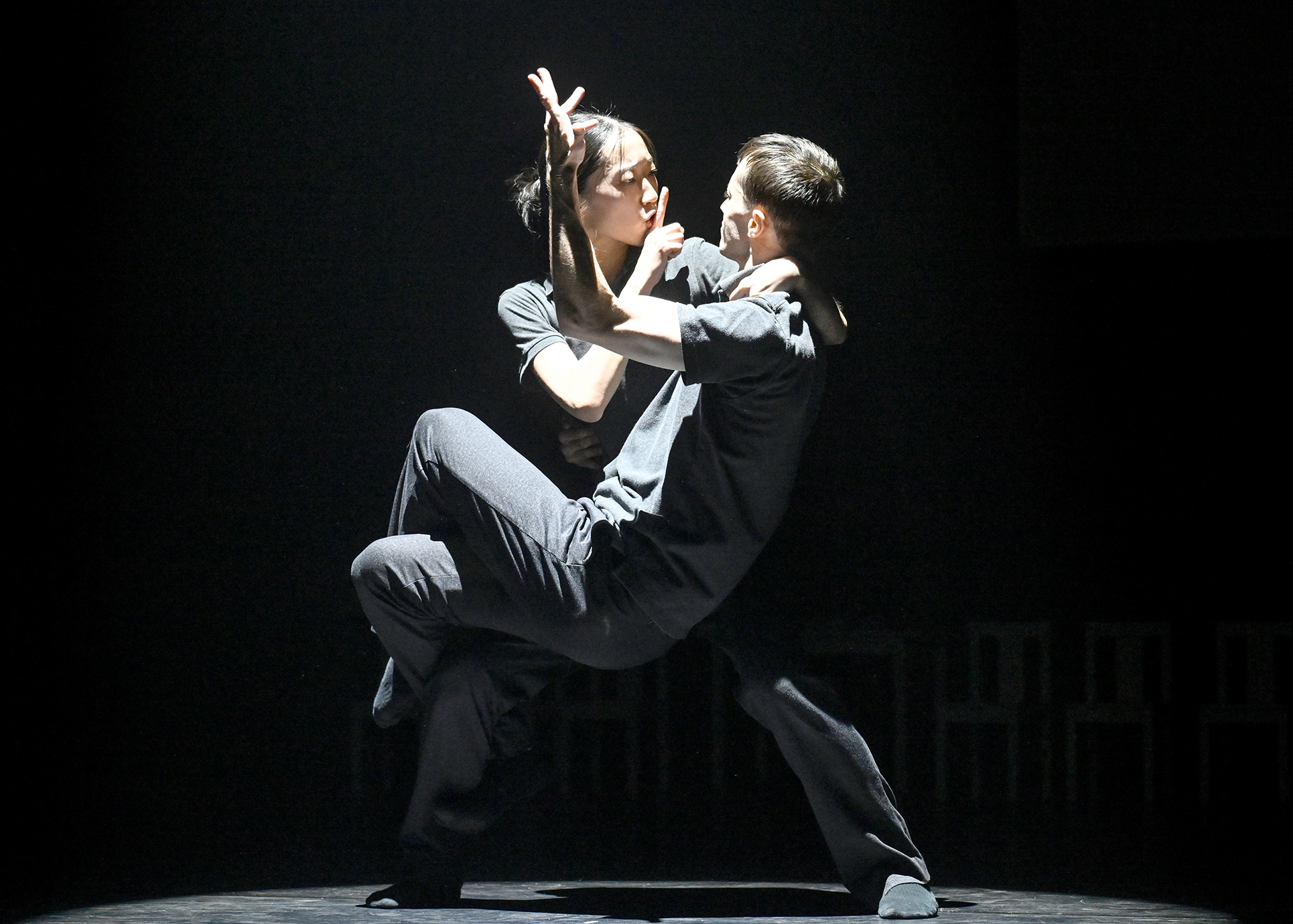 Zwei Tänzer in dunkler Atmospähre und dunkler Kleidung in einger umschlungenen Pose