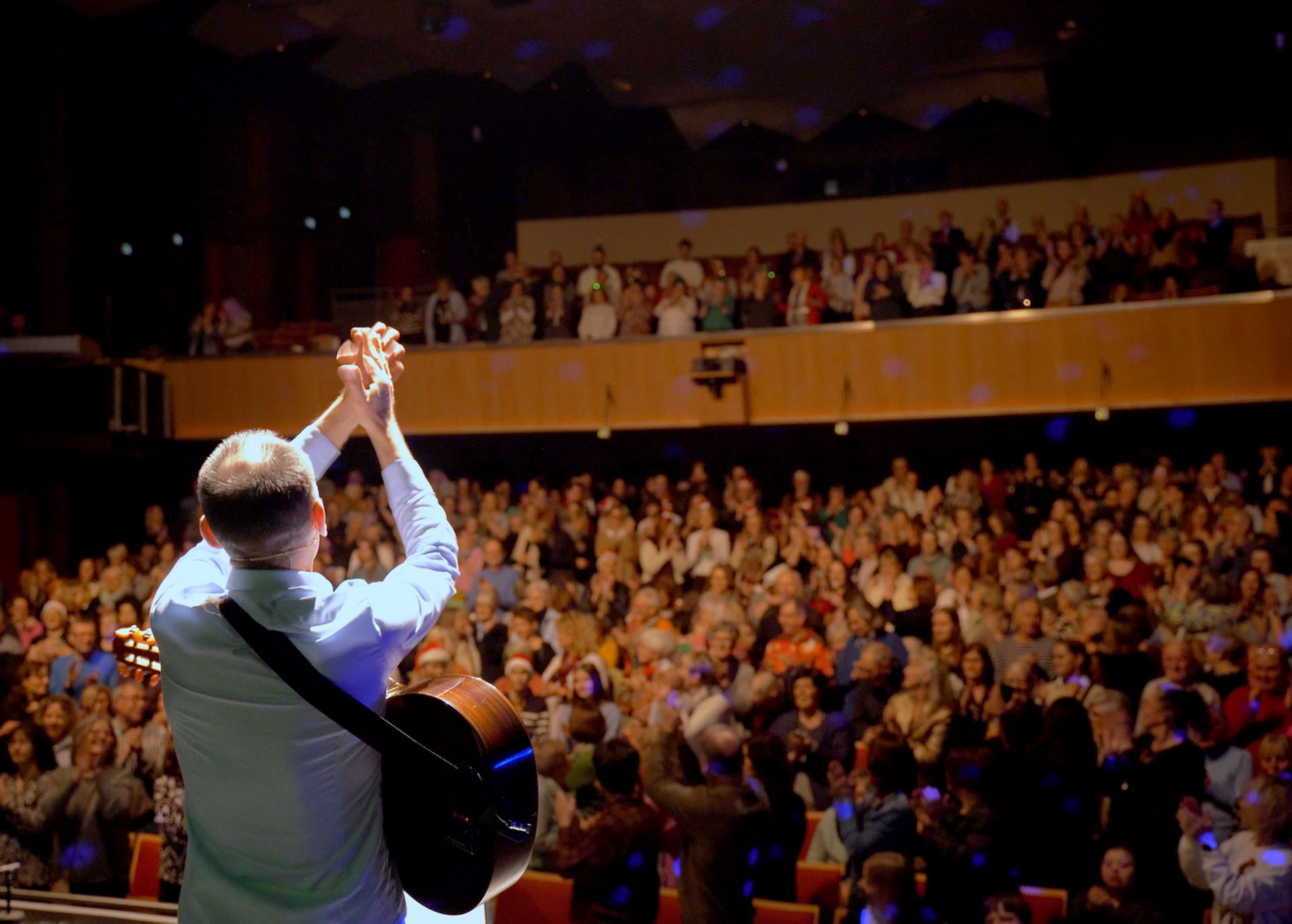 Stefan Nussbaum ist von hinten zu sehen. Er bedankt sich bei dem Publikum, das applaudierend vor ihm steht.