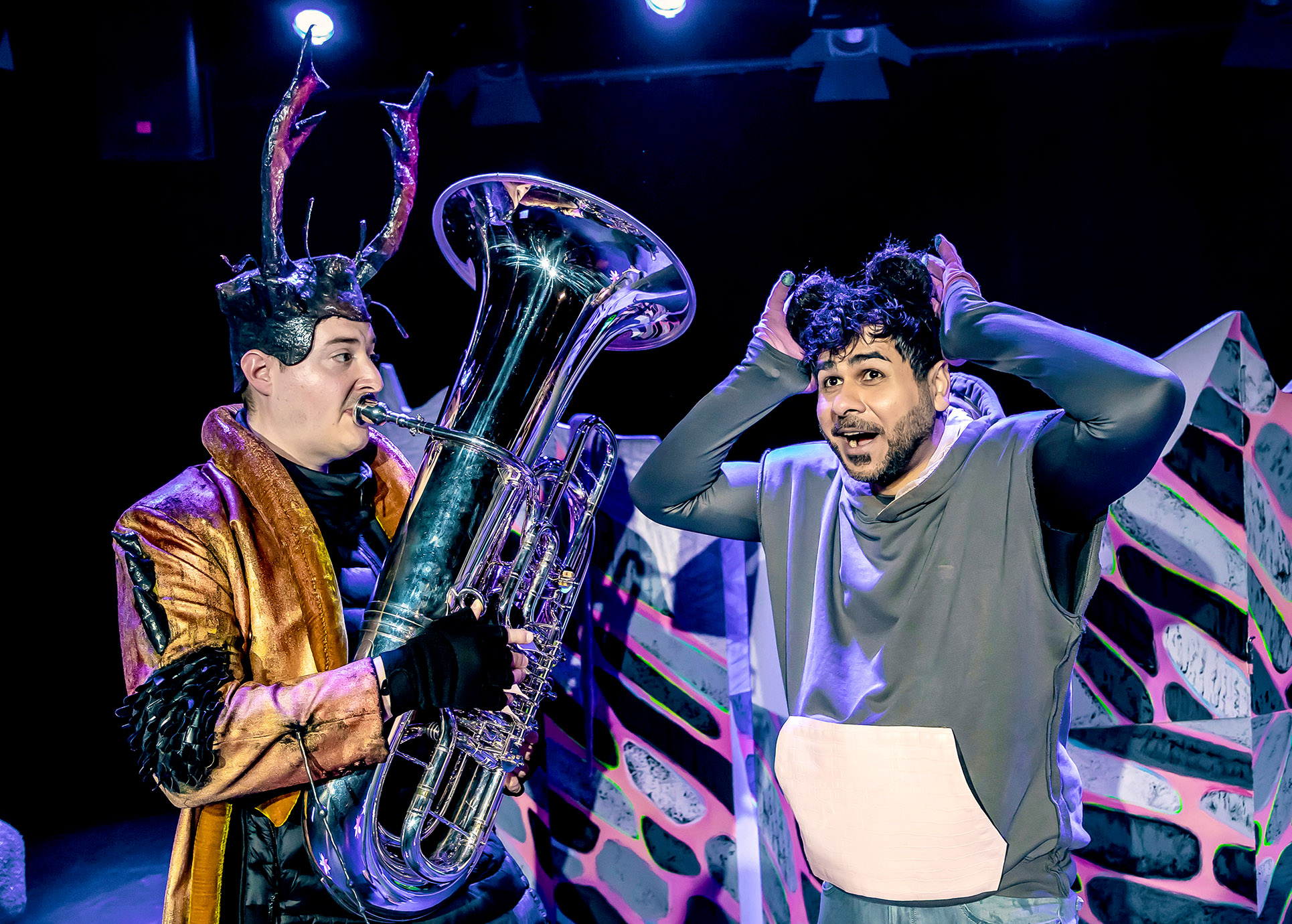 Frederick im Mauskostüm hält die Hände an seine Ohren. Neben ihm ist eine weitere Person als Maus verkleidet mit einer Tuba zu sehen.