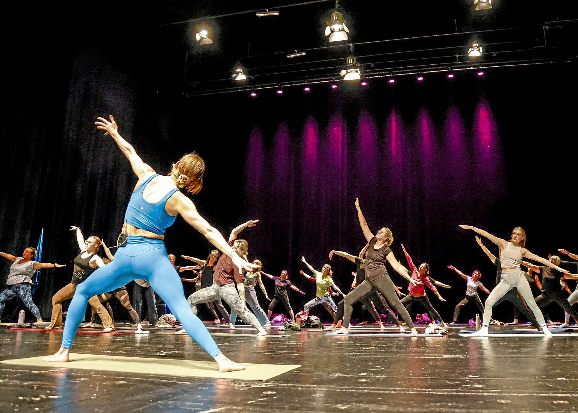 Auf dem Foto sind verschiedene Besucherinnen und Besucher des Gesundheitstages zu sehen, die auf der Bühne an einem Fitness-Workshop teilnehmen.