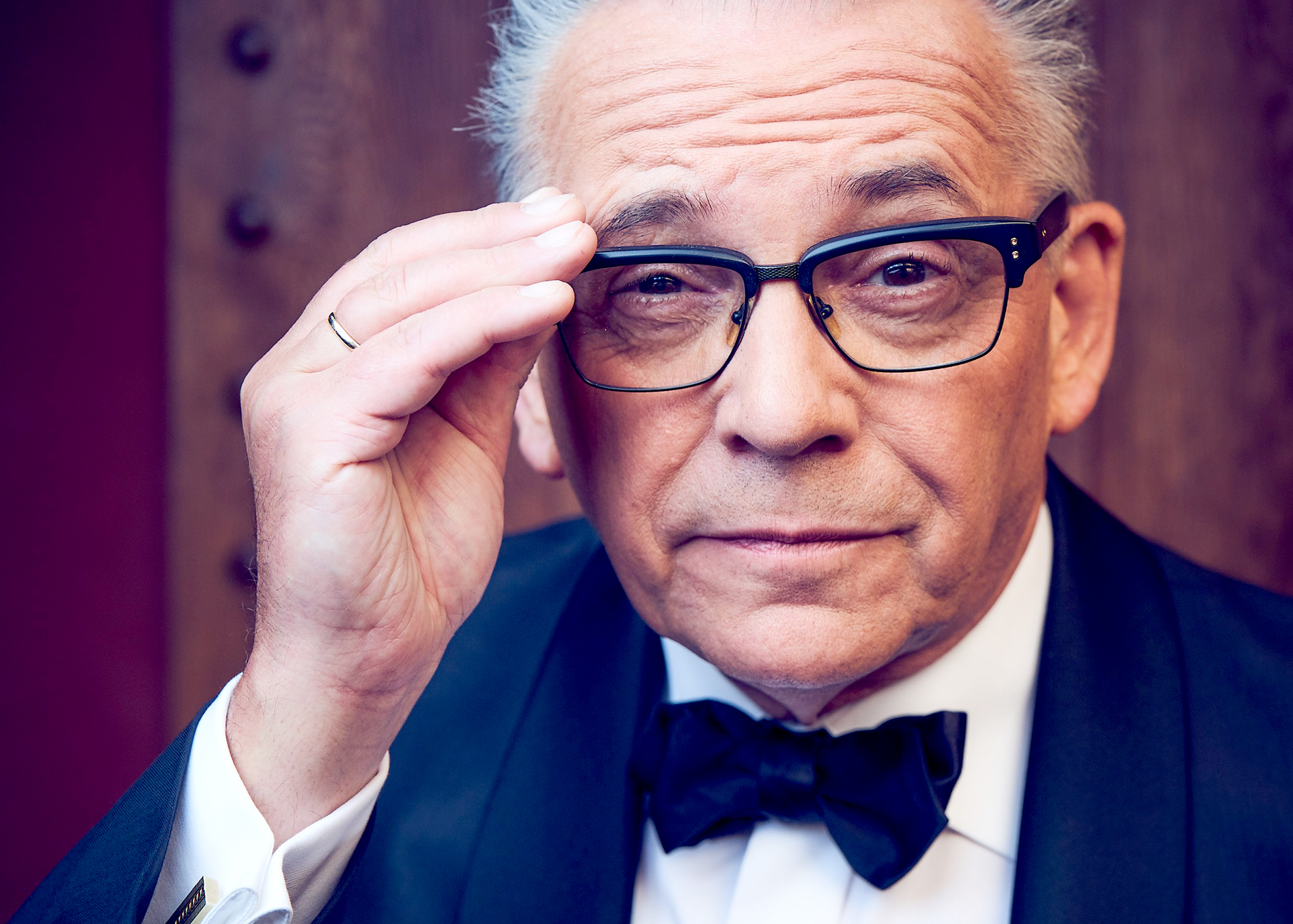 Götz Alsmann greift an seine Brille und schaut verschmitzt in die Kamera.