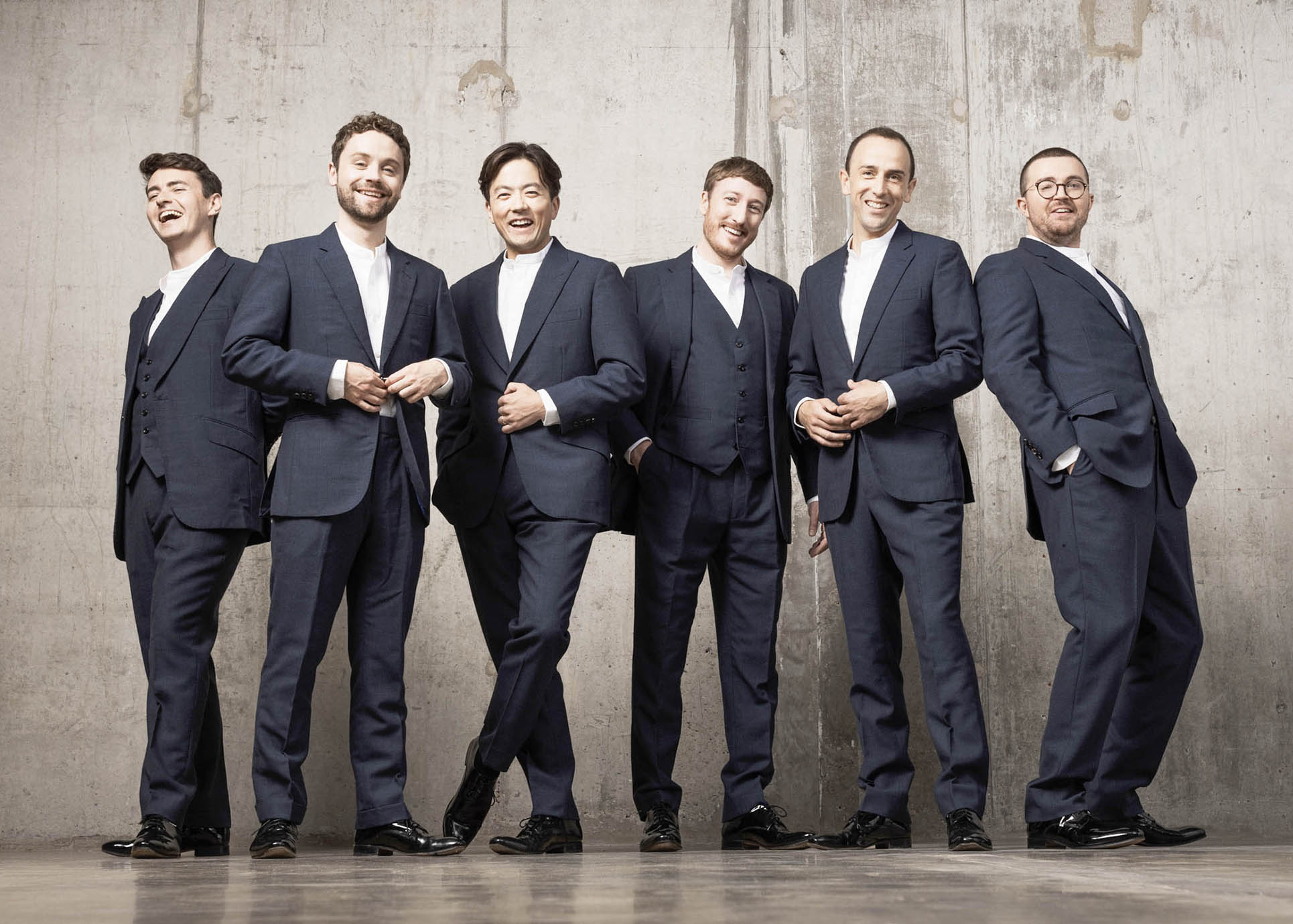 Die sechs Kings Singers tehen in schwarzen Anzügen nebeneinander.