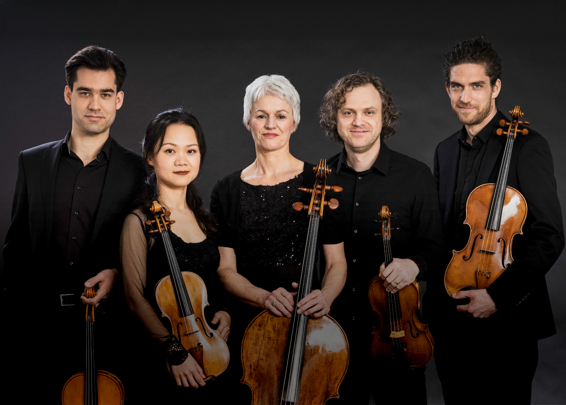 Die Musiker stehen mit ihren Instrumenten auf der Bühne. Alle sind schwarz gekleidet.