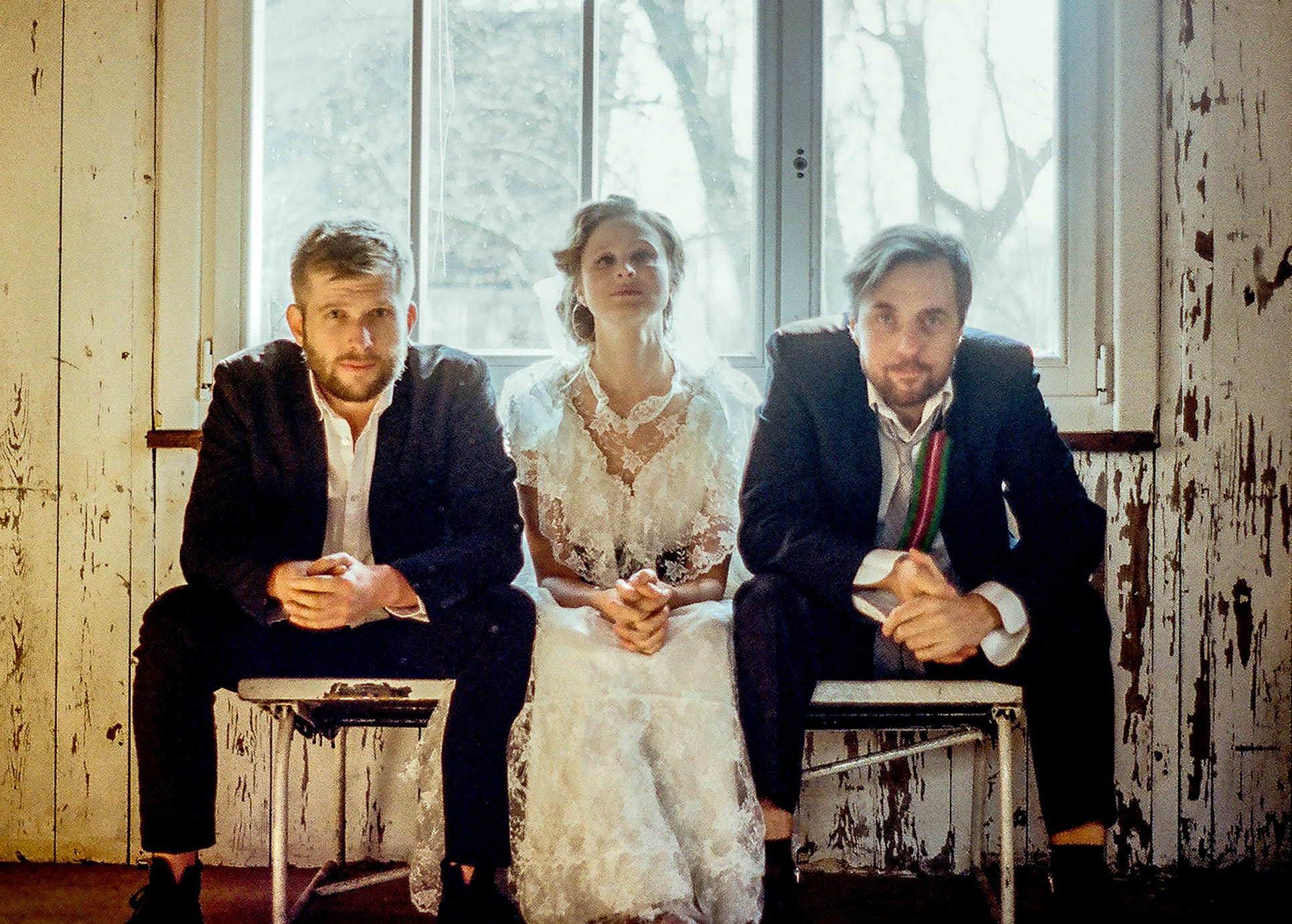 Das Trio WoWaKin sitzt auf Stühlen und schaut auffordernd in die Kamera.