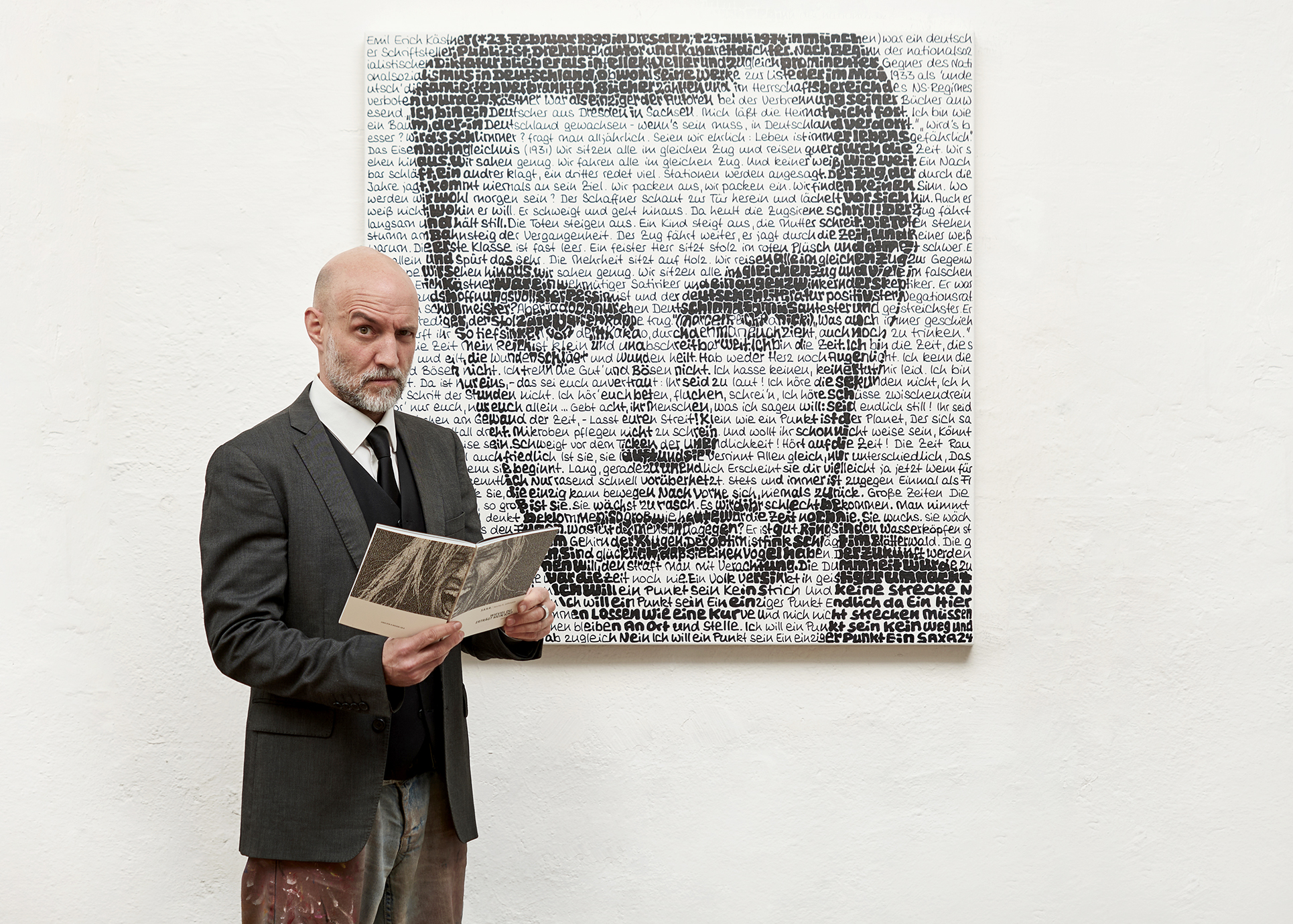 SAXA steht mit dem gleichen Gesichtausdruck wie der hinter ihm aus Worten gemalten Erich Kästner neben seinem Bild.