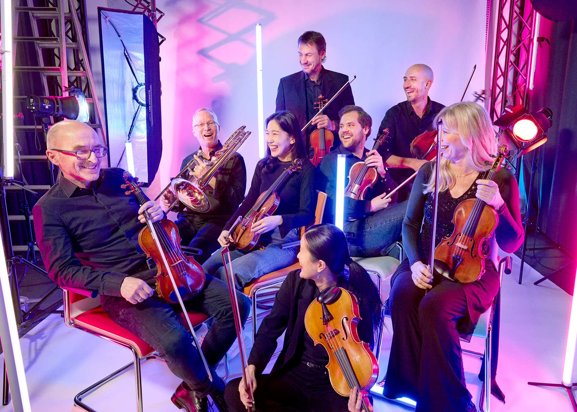 Die Mitglieder des Orchesters sitzen in einem Theatersaal.